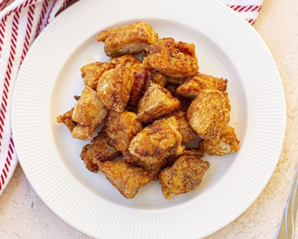 A plate of fried chicken breast pieces on a kitchen countertop.