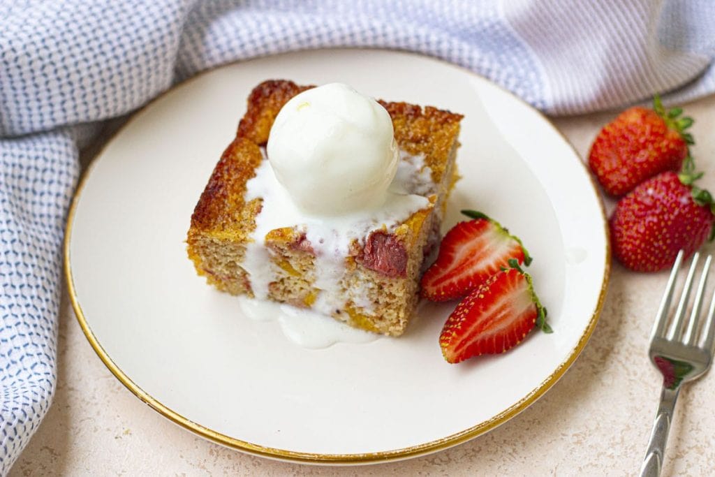 A piece of cake with ice cream and strawberries on a plate.