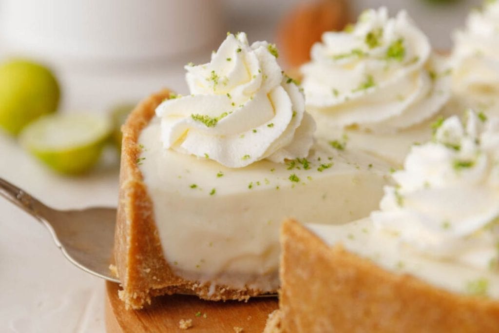 A slice of key lime pie, perfect for Spring Desserts, topped with whipped cream and lime zest.