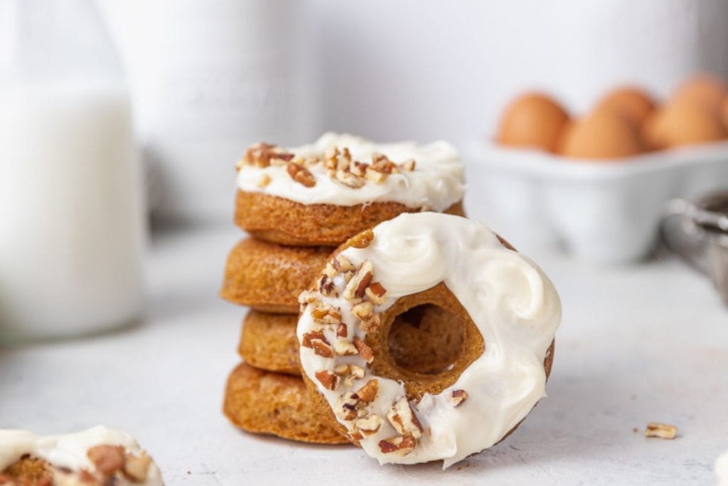 Spring desserts: Stack of glazed doughnuts with chopped nuts on top, with milk and eggs in the background.