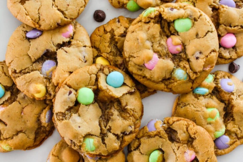 Chocolate chip cookies with colorful candy pieces on a white surface perfect for spring desserts.