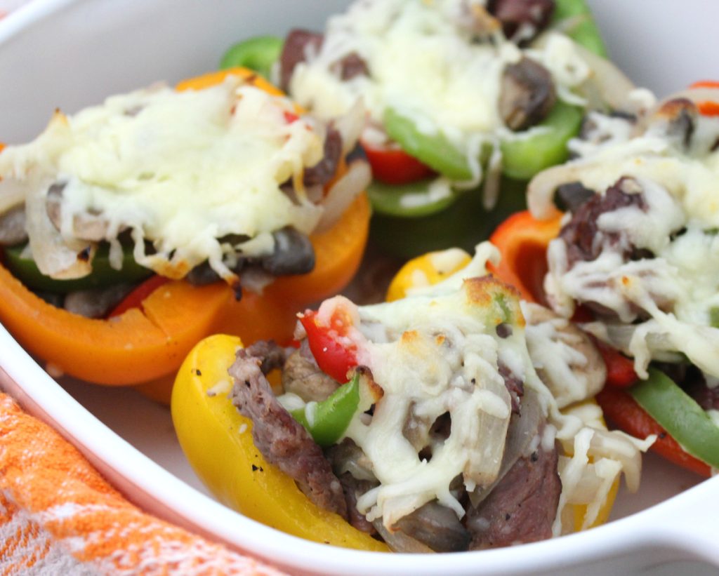 A dish of stuffed bell peppers filled with a mixture of meats, vegetables, and topped with melted cheese, served in a white bowl.